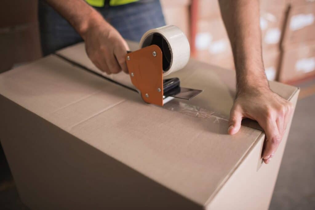 A professional packer sealing a cardboard