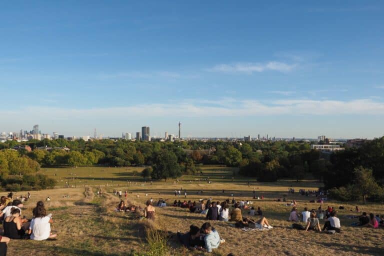 People in Primrose Hill Park under the sun in the concept of 'best parks and green spaces in North London'.