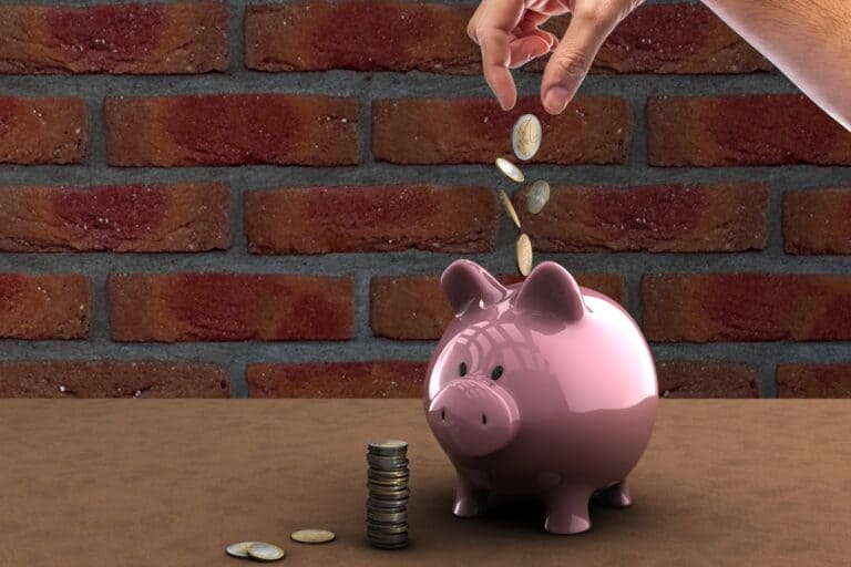 A glossy piggy bank with coins falling into it in the concept of 'how to save money when moving to North London'.