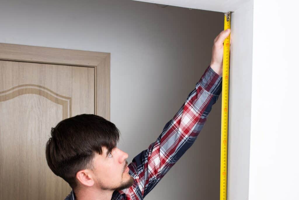 A man measuring the height of the doorway