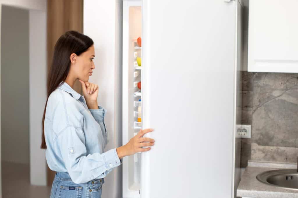 A woman in front of a large white fridge