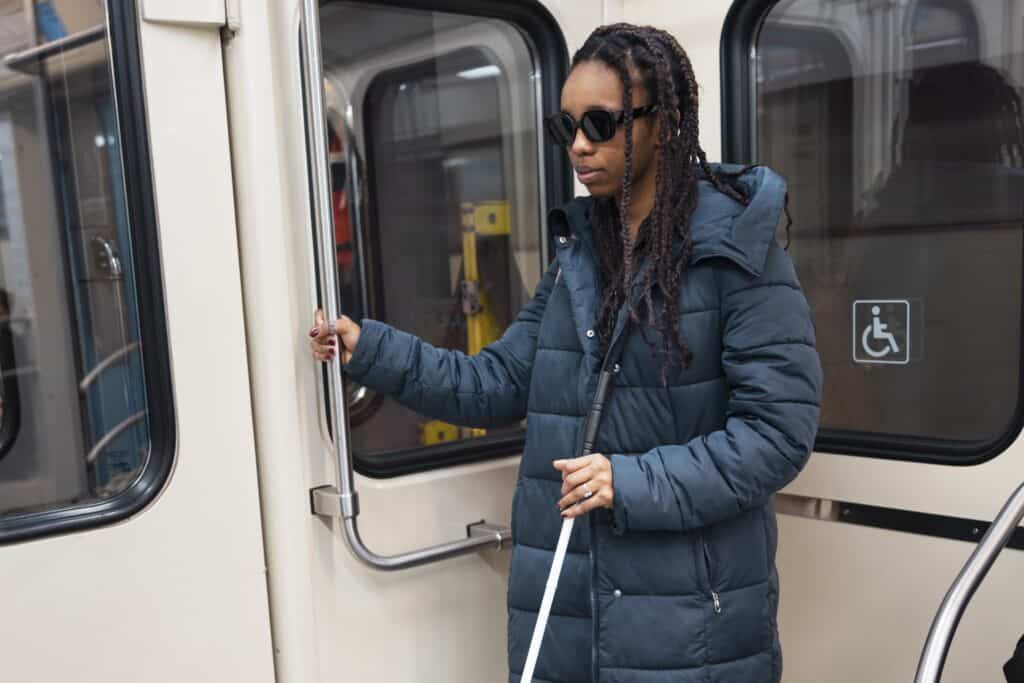 A blind woman on a train with a PWD sign on the glass behind her