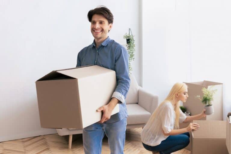 A young couple surrounded by cardboard after moving house in the concept of 'What to Do with Packing Materials After Moving House to North London'.